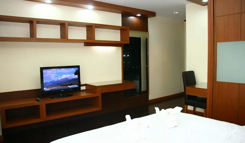 房间 出租在Khlong Toei, Bangkok - 卧室内置木质电视墙与书桌，嵌灯照明