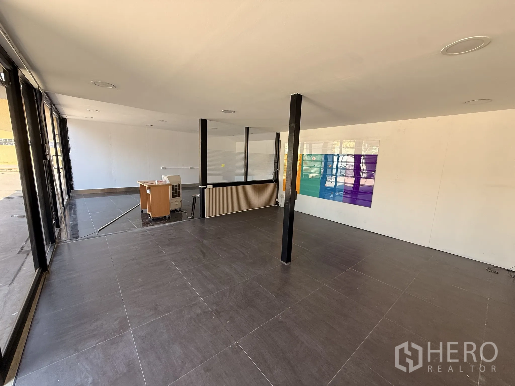 Warehouse for rent in Lat Krabang, Bangkok - Alternate angle of the spacious glass-fronted office with pillars and glossy floor tiles.