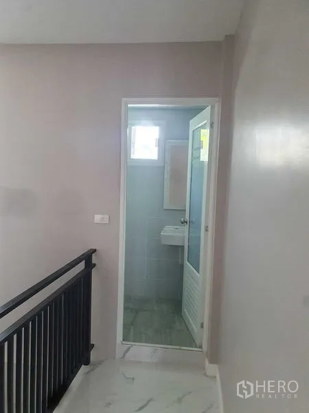 Home Office for rent in Suan Luang, Bangkok - Hallway leading to a tiled bathroom with a white door and window.