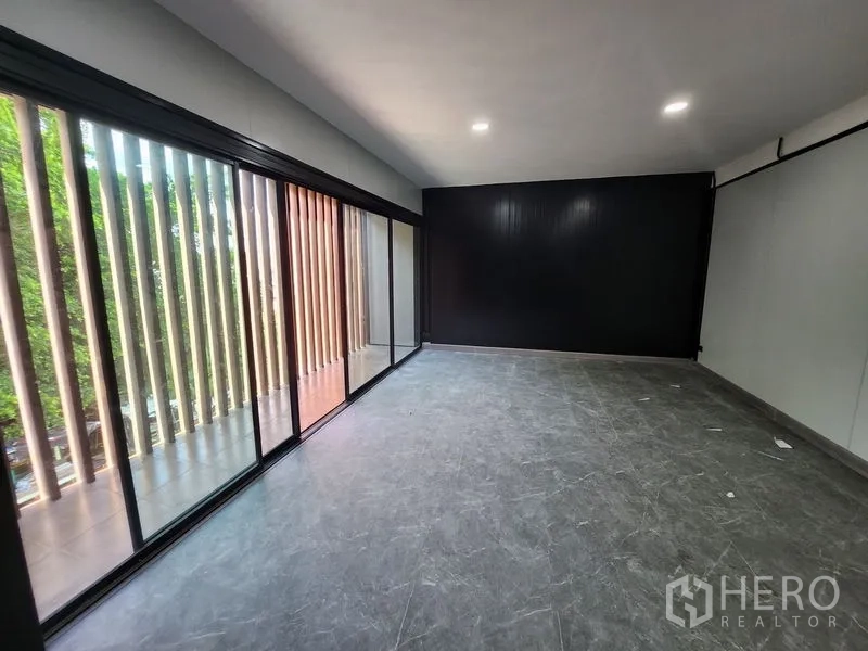 Warehouse for rent in Lam Luk Ka, Pathum Thani - Bright office room with floor-to-ceiling glass and a black feature wall.