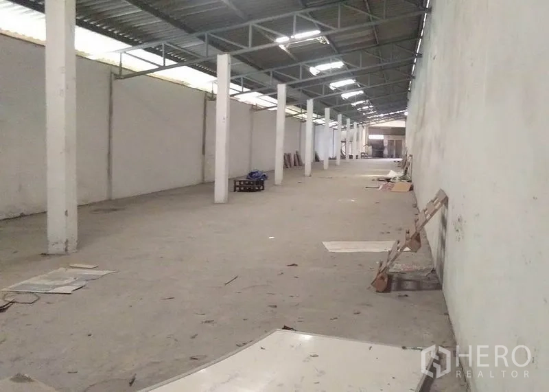 Factory for rent in Bang Phli, Samut Prakan - Long warehouse aisle with columns and metal roof featuring skylight panels for ventilation.