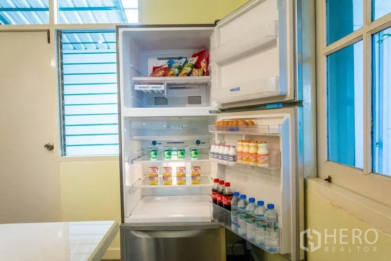 Home Office for rent in Suan Luang, Bangkok - Open refrigerator stocked with drinks and snacks in the kitchen.