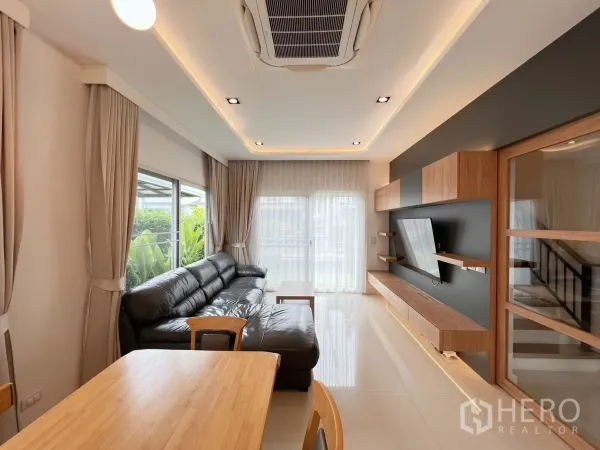 Detached House for rent or sale in Khlong Luang, Pathum Thani - Bright living area with black leather sofa, large windows and sliding door to garden.