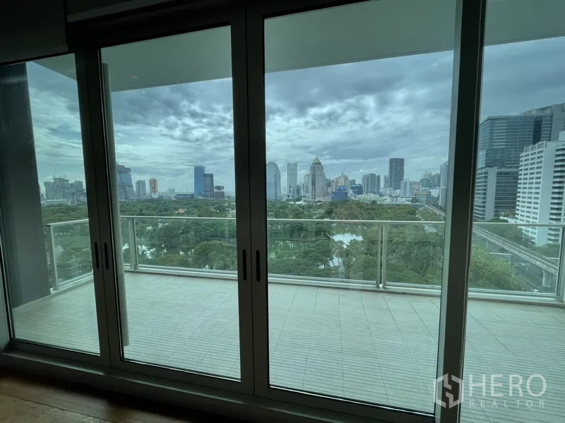 Condominium for rent in Pathum Wan, Bangkok - Sliding glass doors open to a balcony with park and city views.