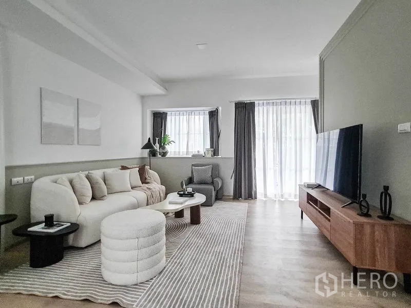 ทาวน์เฮาส์ ให้เช่าในPrawet, Bangkok - ห้องนั่งเล่นสว่าง โซฟาโค้ง ชั้นวางทีวี พรมลายทาง และผ้าม่านโปร่ง