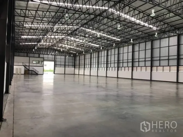 Warehouse for rent in Bang Phli, Samut Prakan - Open warehouse floor with ventilated side walls, steel beams and bright overhead lights.