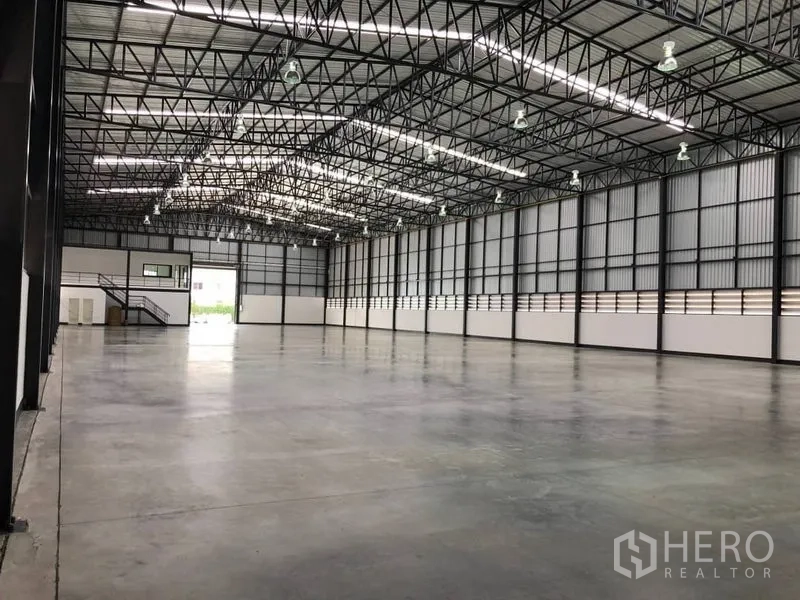 Warehouse for rent in Bang Phli, Samut Prakan - Open warehouse floor with ventilated side walls, steel beams and bright overhead lights.