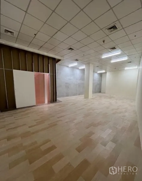 Retail Space for rent in Watthana, Bangkok - Spacious unit with support column, fluorescent lighting and a partially finished partition wall.