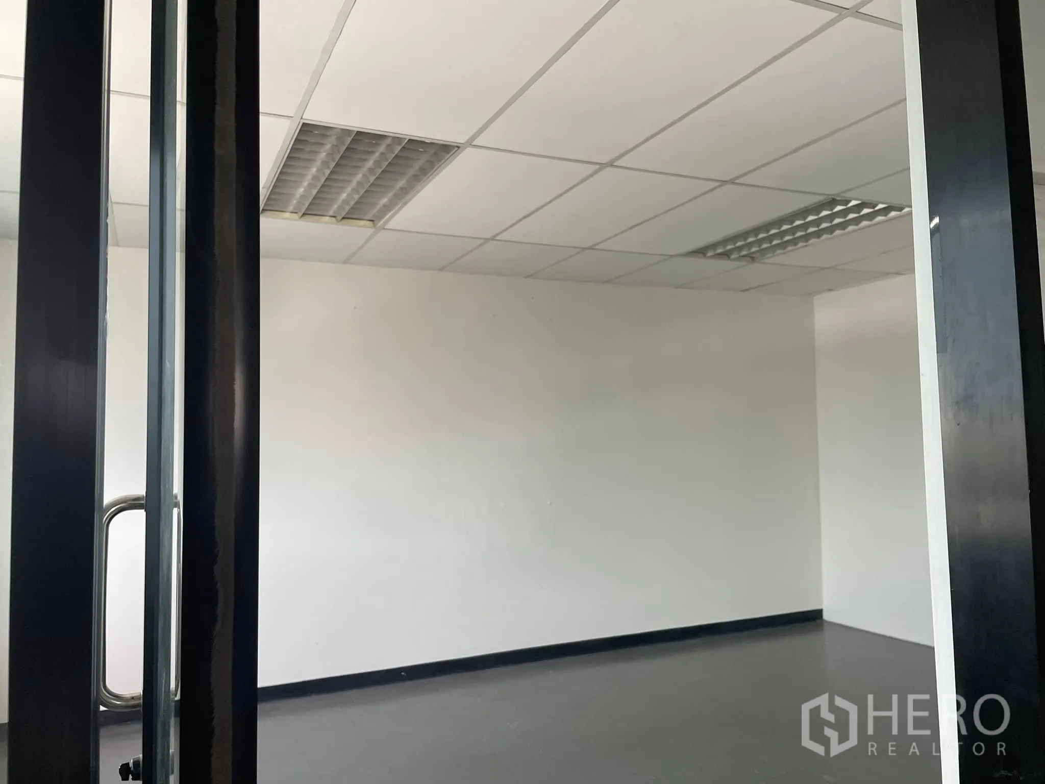 Office Space for rent in Lat Phrao, Bangkok - Small office room with glass door, white walls, and grid ceiling lights.