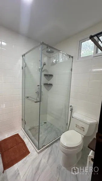 Detached House for rent in Watthana, Bangkok - Modern bathroom with glass shower enclosure and white wall tiles.