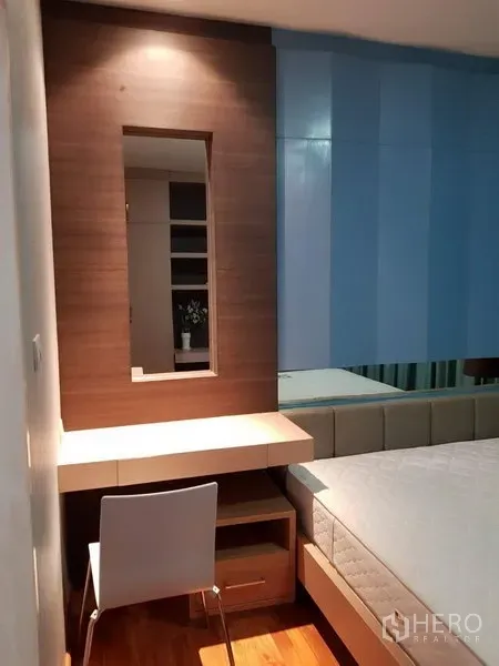 Townhouse for rent in Phra Khanong, Bangkok - Compact bedroom corner with vanity desk, mirror and chair beside the bed.