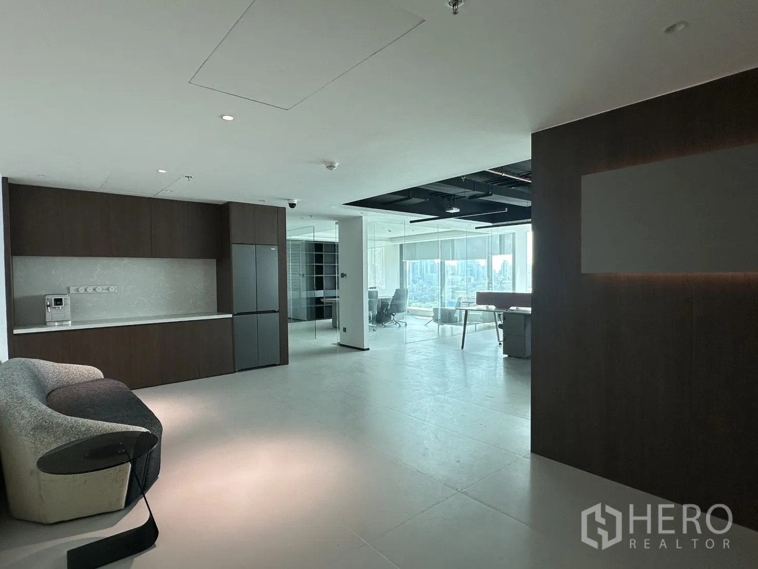 Office Space for rent in Din Daeng, Bangkok - Pantry with built-in cabinets, counter, refrigerator, and a curved sofa in the breakout area.