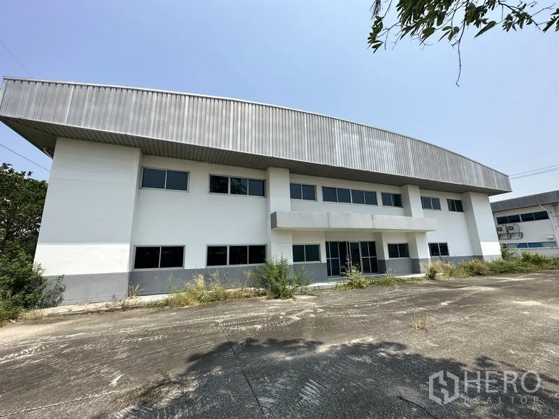 Factory for rent in Chon Buri - Front façade of the factory with glass main entrance and parking apron.