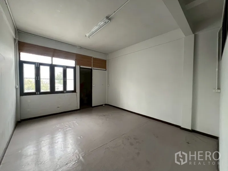 Shophouse for rent in Phra Khanong, Bangkok - Simple bedroom or office room with window and door, neutral finishes.