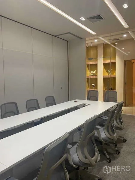 Office Space for rent in Huai Khwang, Bangkok - Modern conference room with long white table, gray chairs and illuminated display shelves.