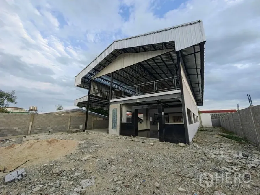 工厂 出租或出售在Mueang Samut Prakan, Samut Prakan - 两层厂房外观，悬挑金属屋顶与入口门面。