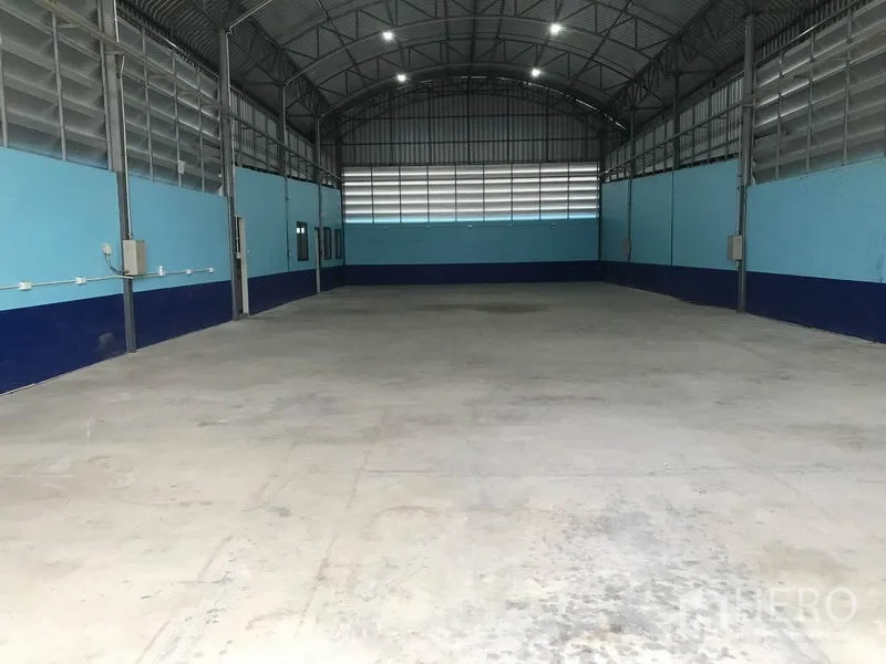 Warehouse for rent in Khlong Luang, Pathum Thani - Spacious warehouse interior with high arched steel roof, ventilation louvres and smooth concrete floor.