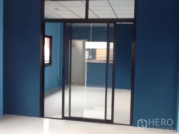Warehouse for rent in Bang Kapi, Bangkok - Glass-partitioned blue office room with sliding doors and glossy floors inside the warehouse.