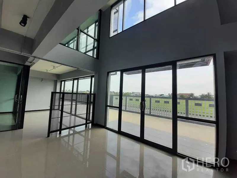 Factory for rent or sale - Double-height office space with floor-to-ceiling windows opening to a balcony and open green views.