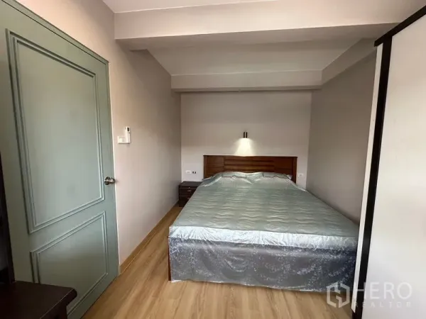 联排别墅 出租在Phra Khanong, Bangkok - 主卧配双人床、木地板、床头柜与壁灯，风格简洁。