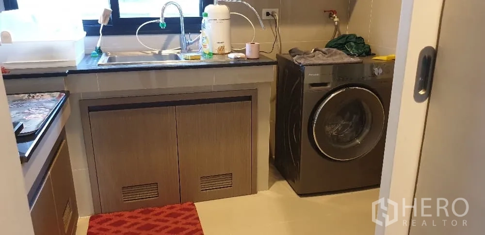 Detached House for rent or sale in Lam Luk Ka, Pathum Thani - Kitchen and laundry with sink, black countertop and washing machine.