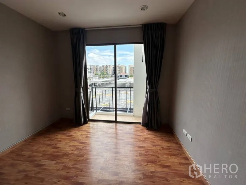 Townhouse for rent or sale in Phra Khanong, Bangkok - Bedroom with sliding glass door opening to a small balcony and community view.