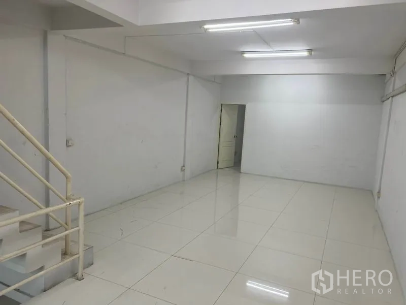 Shophouse for rent in Bang Rak, Bangkok - Spacious level with staircase and doorway, bright fluorescent lighting.