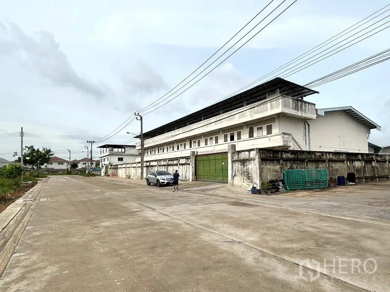 货栈 出租在Bang Khun Thian, Bangkok - 仓库门前宽阔的混凝土道路与围墙大门。