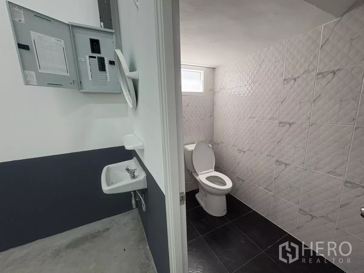 Factory for rent or sale in Bang Bua Thong, Nonthaburi - Ground-floor restroom and utility sink adjacent to the electrical control panel.