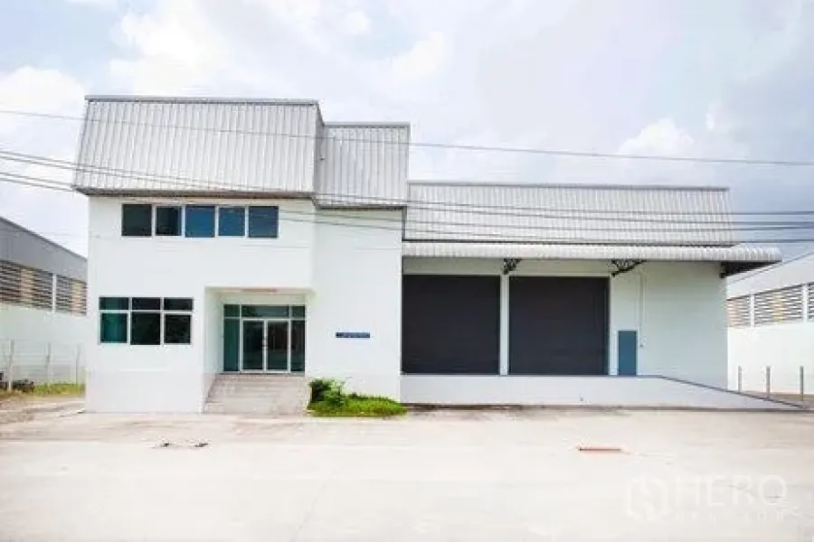 货栈 出租在Bang Phli, Samut Prakan - 立面展示双卷帘门、带顶装卸月台及前置办公区与停车铺面。