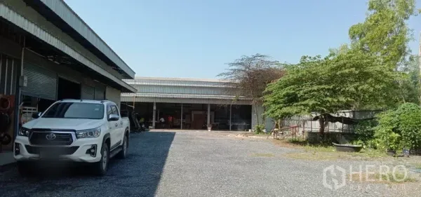 货栈 出租在Khlong Sam Wa, Bangkok - 两侧仓库之间的宽阔碎石庭院，有树荫与开放式装卸位。