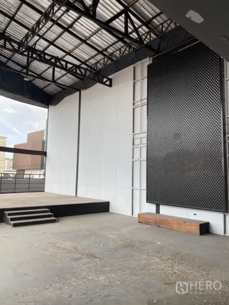 Showroom for rent in Lat Phrao, Bangkok - Open industrial floor with a small raised stage and steel truss roof.