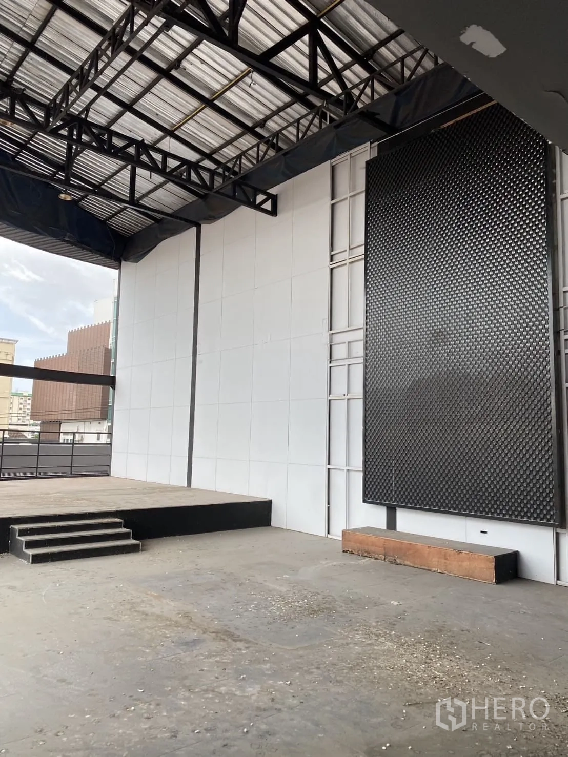 Showroom for rent in Lat Phrao, Bangkok - Open industrial floor with a small raised stage and steel truss roof.