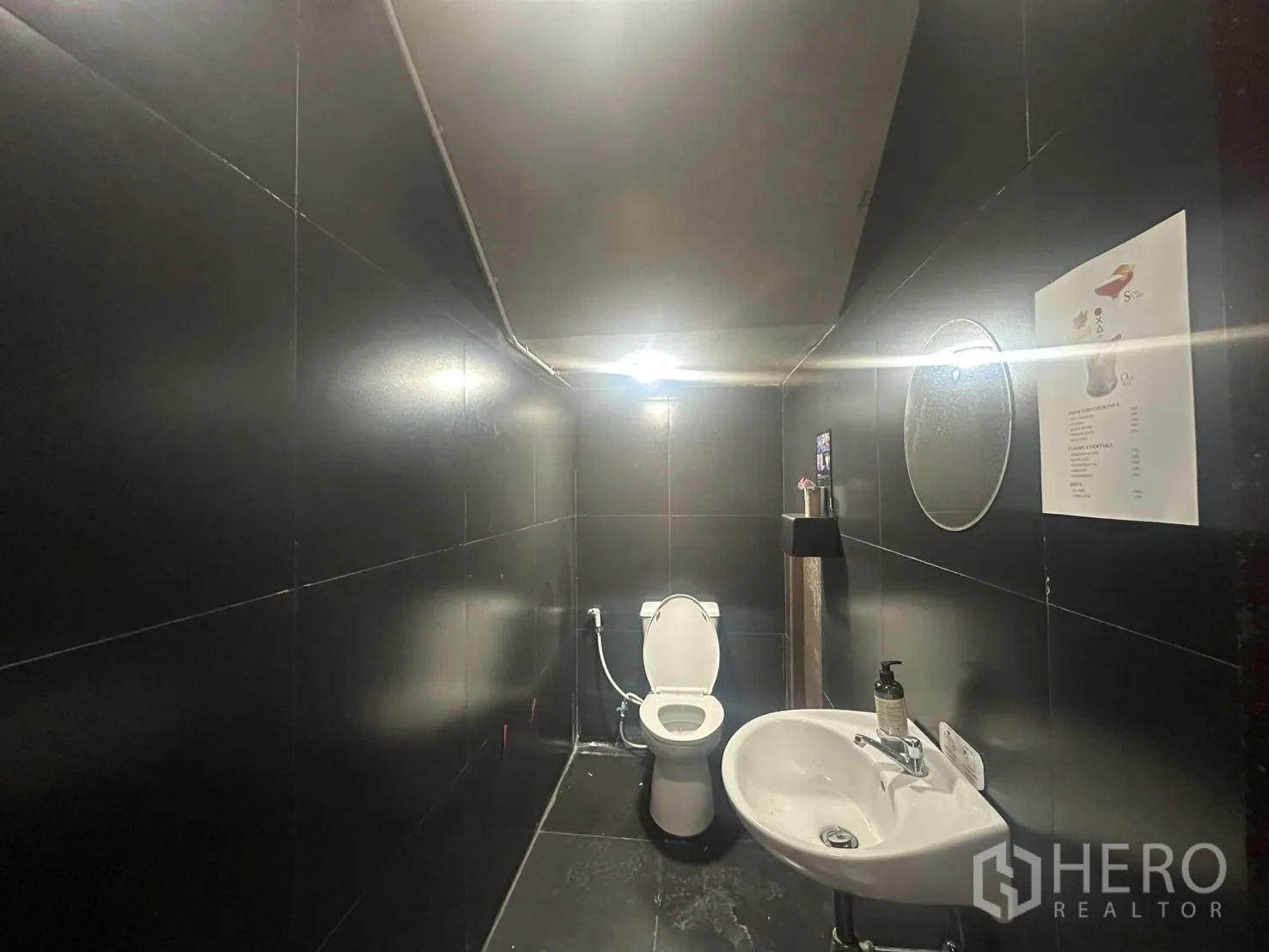Home Office for rent in Pathum Wan, Bangkok - Black-tiled restroom with toilet and wall-mounted sink, ready for staff or customers.