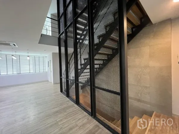 Home Office for rent in Bueng Kum, Bangkok - Open-plan home office with metal mesh feature wall and floating staircase.