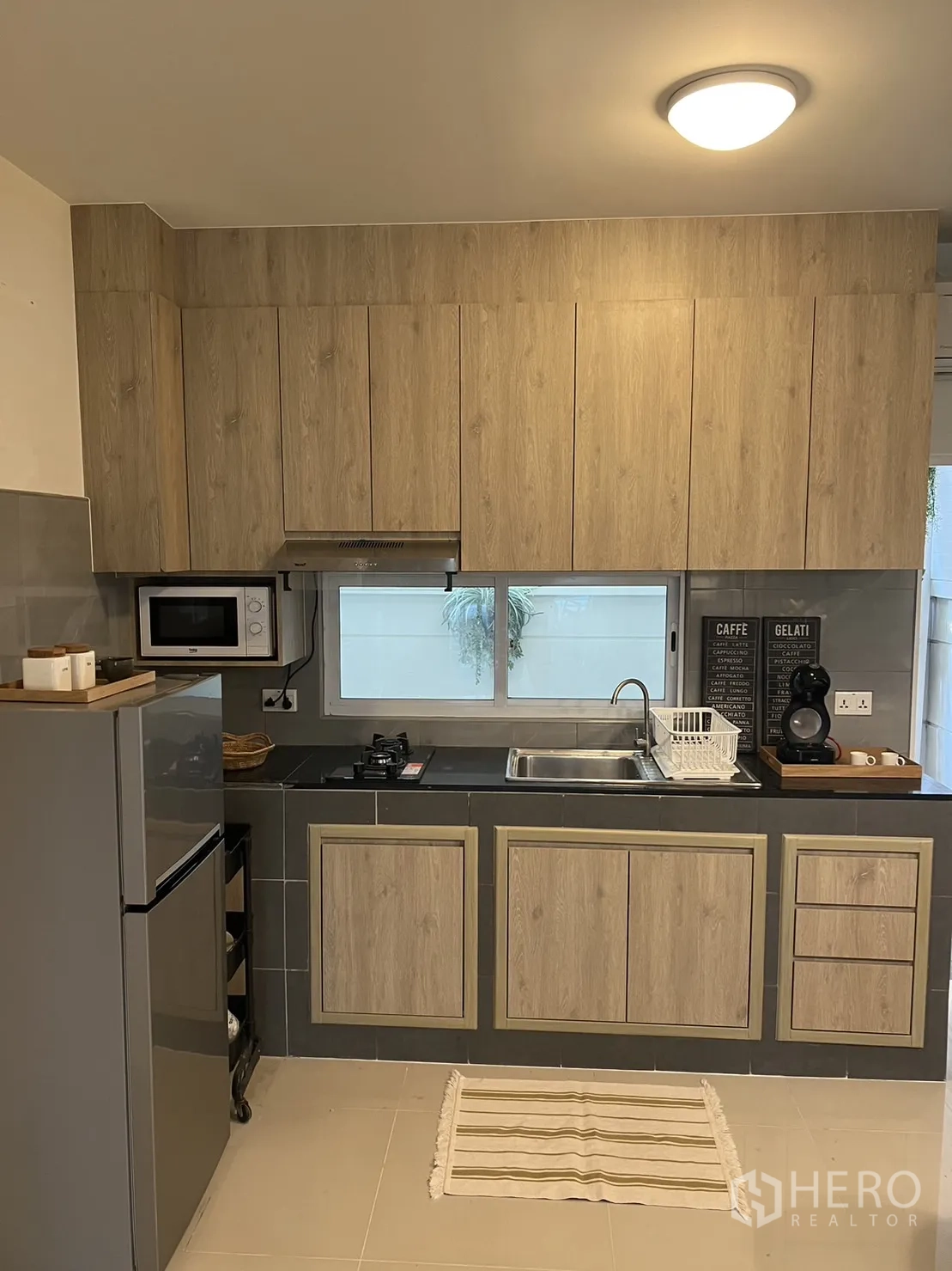联排别墅 for rent in Suan Luang, Bangkok - 紧凑厨房，设吊柜、燃气灶、烟机与冰箱。