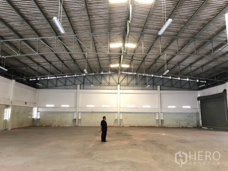 Factory for rent in Nonthaburi - Large clear-span warehouse interior with bright lights and concrete floor.