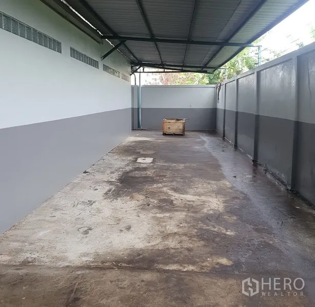 Factory for rent in Saphan Sung, Bangkok - Covered side yard with concrete floor and high perimeter walls suitable for loading or storage.