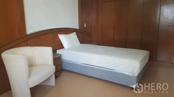 Condominium for rent in Khlong Toei, Bangkok - Guest bedroom with single bed, lounge chair, and built-in wardrobes.