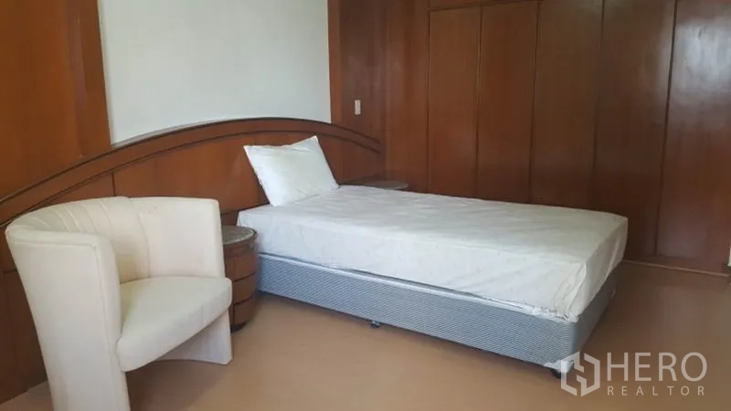 Condominium for rent in Khlong Toei, Bangkok - Guest bedroom with single bed, lounge chair, and built-in wardrobes.