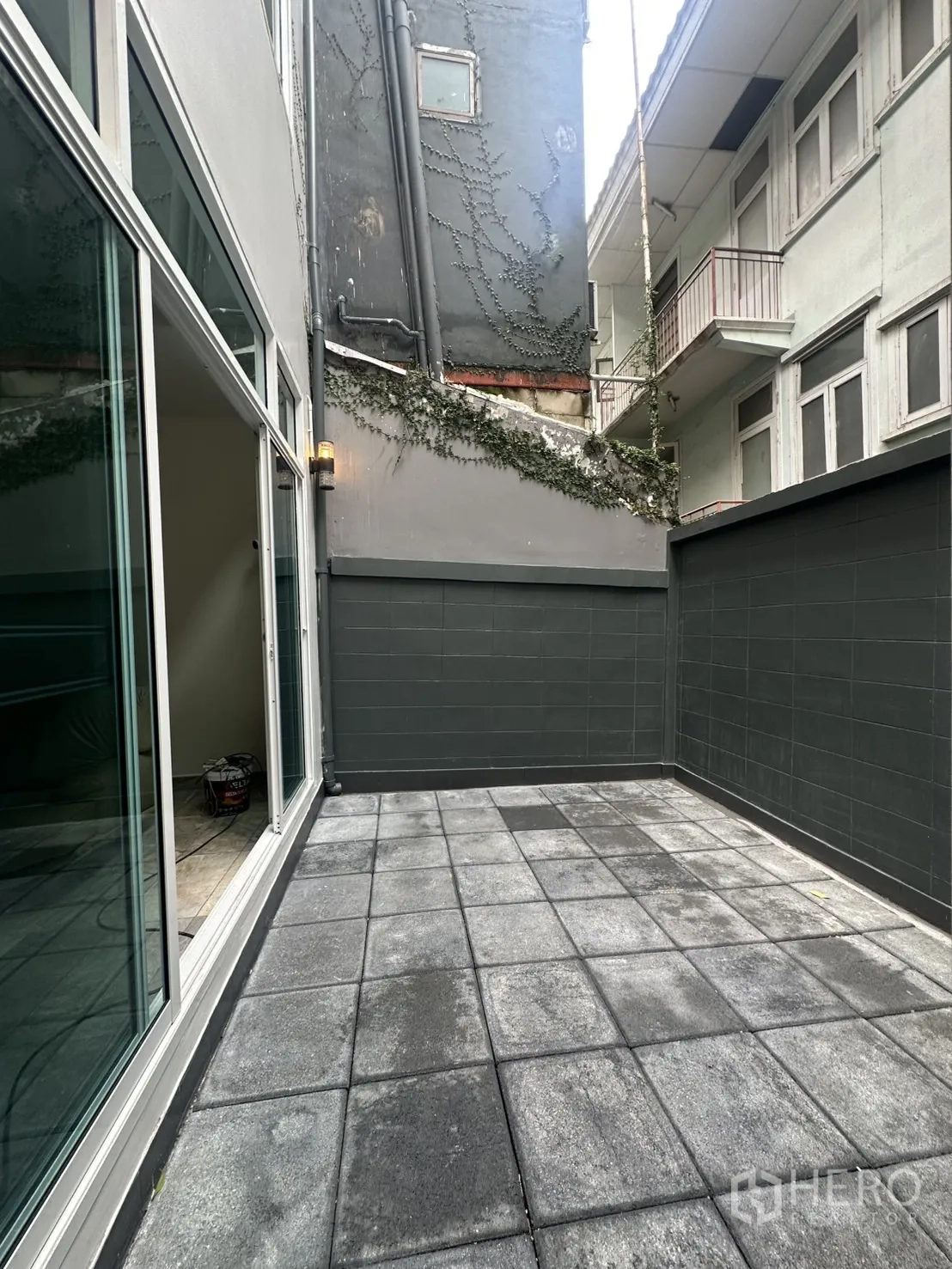 Home Office for rent in Khlong Toei, Bangkok - Enclosed rear patio with high privacy walls and floor tiles.