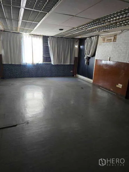 Shophouse for rent in Watthana, Bangkok - Open-plan upper floor with drop ceiling lights, window and mixed wall finishes.