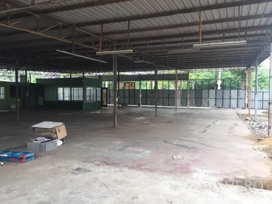 Warehouse for rent in Pathum Thani - Open-plan warehouse with steel roof, concrete floor and a green office cabin.