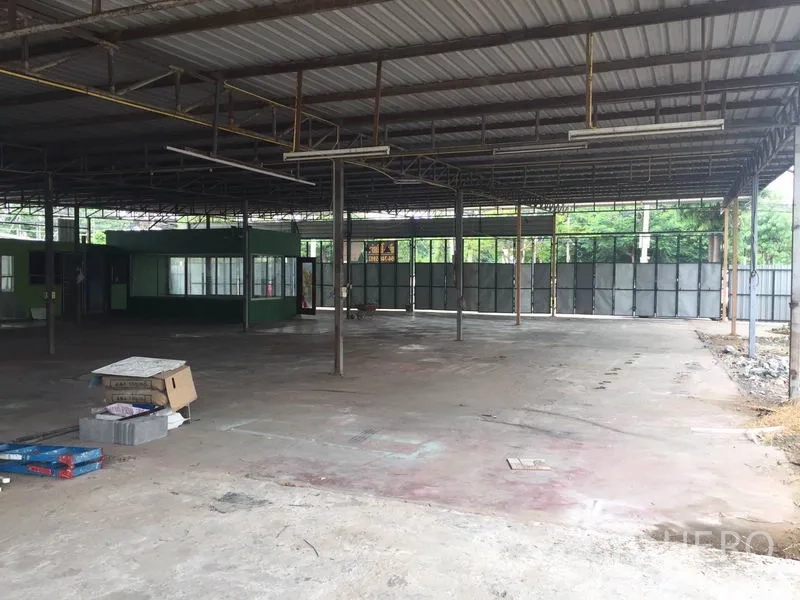 Warehouse for rent in Pathum Thani - Open-plan warehouse with steel roof, concrete floor and a green office cabin.