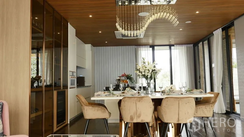 Detached House for sale in Prawet, Bangkok - Formal dining room beneath crystal chandelier with glass‑front cabinetry and sliding doors.