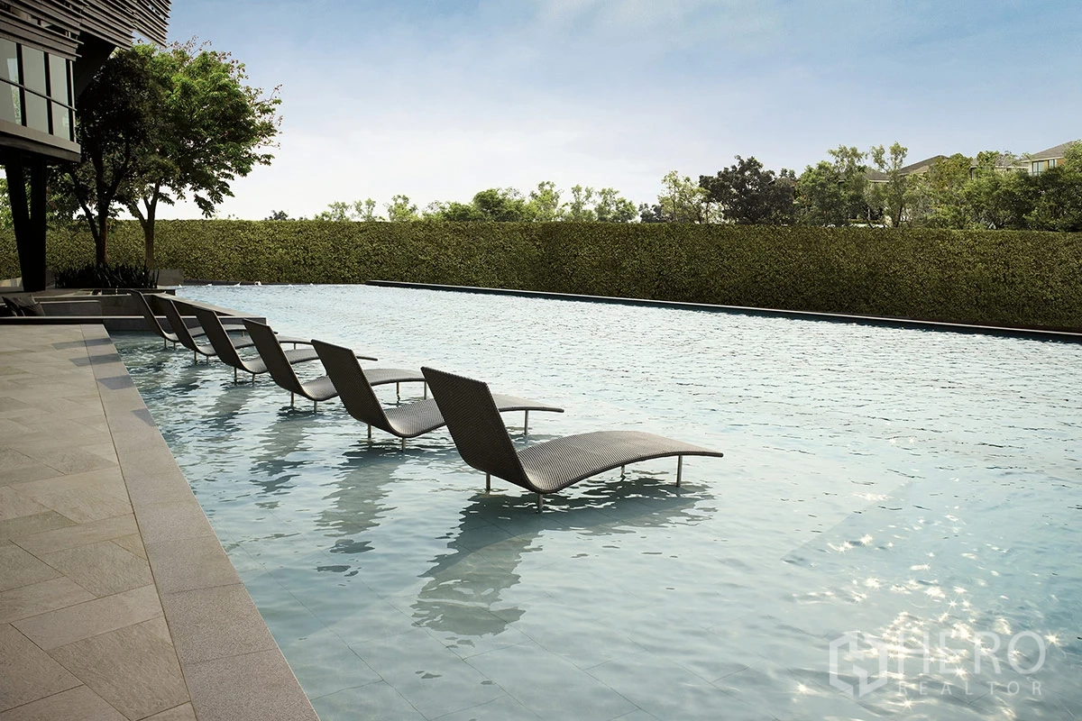 Detached House for rent or sale in Pathum Thani - Long shallow pool with reclined loungers facing a hedged boundary.