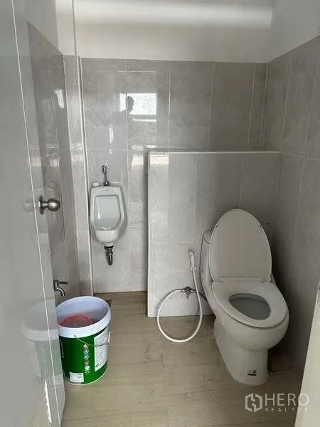 Warehouse for rent in Khlong Sam Wa, Bangkok - Clean tiled restroom with toilet, urinal and handheld bidet spray.
