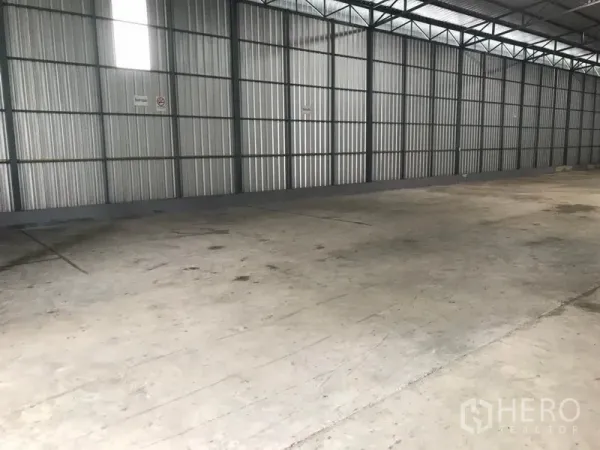 Warehouse for rent in Wang Thonglang, Bangkok - Open storage bay with corrugated metal walls, skylight panels and smooth concrete flooring.