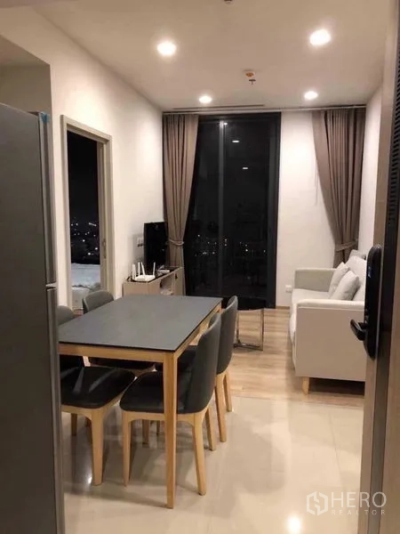 Condominium for rent in Khlong Toei, Bangkok - Dining area flowing to living room with floor-to-ceiling sliding door and neutral decor.