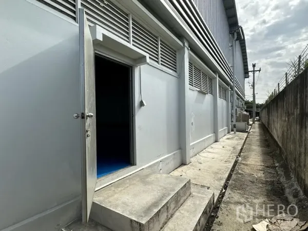工厂 出租在Khlong Luang, Pathum Thani - 厂房侧面服务入口与混凝土通道，墙体设百叶通风口。